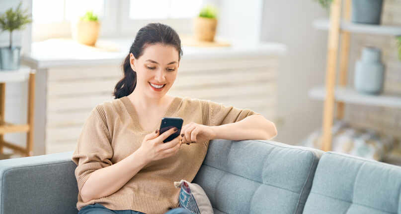 Frau mit Handy auf Sofa